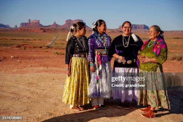 famiglia multigenerazionale di donne navajo che interagiscono insieme a forrest gump hill nella monument valley indossando abiti tradizionali in una soleggiata mattina autunnale - abiti da cerimonia foto e immagini stock