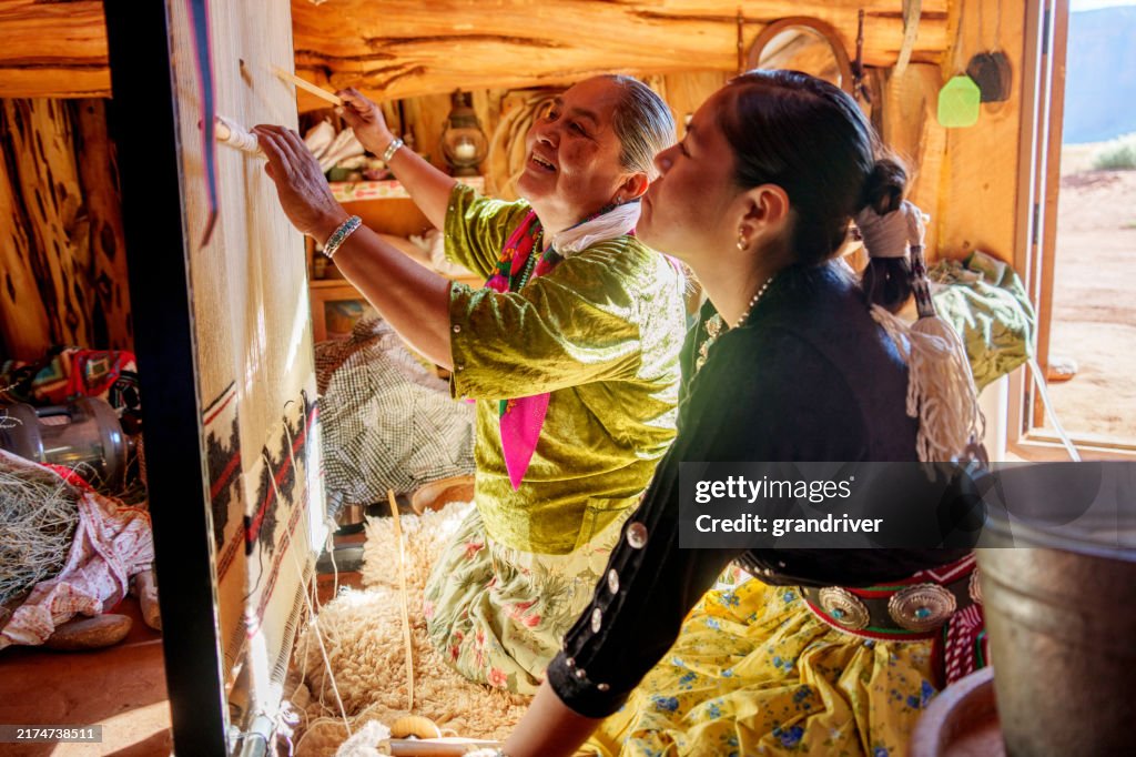A Navajo Grandmother Teaching Her Teenage Granddaughter How To Weave On A Loom in Monument Valley