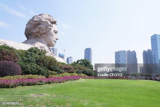 Tourists raise the five-star red flag and take photos in front of the Mao Zedong Youth Art Sculpture to celebrate China's National Day on September...