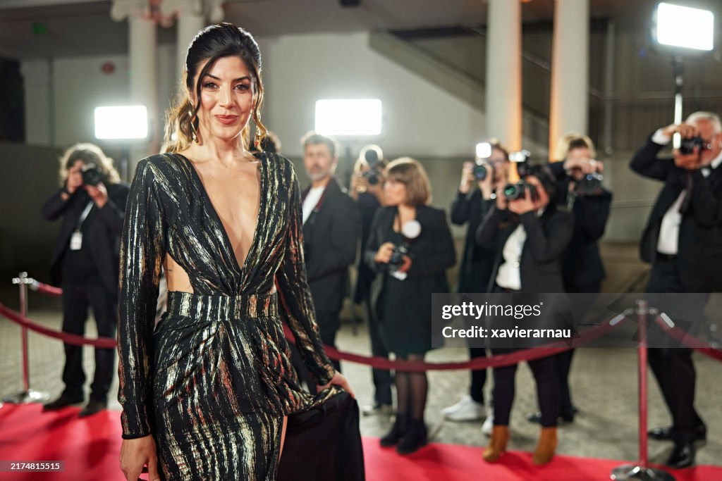Elegant brunette in black and gold gown on red carpet