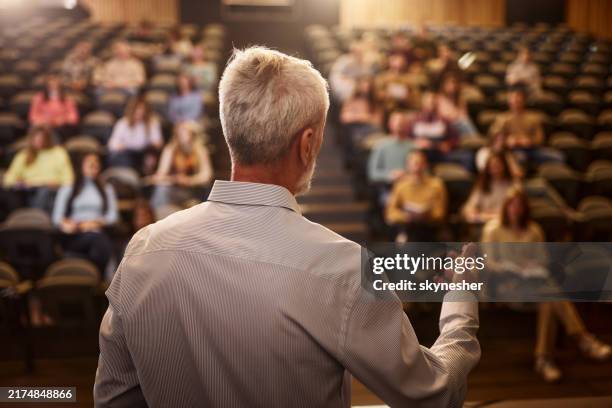 rückansicht eines reifen professors, der in einer klasse im hörsaal spricht. - professor stock-fotos und bilder