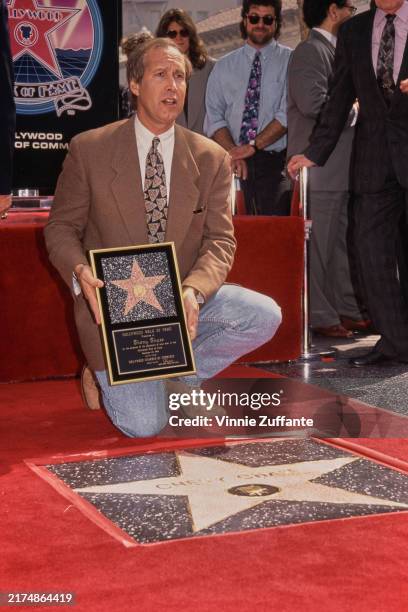 American comedian and actor Chevy Chase, wearing a brown blazer over a white shirt with a patterned tie and jeans, attends his Hollywood Walk of Fame...