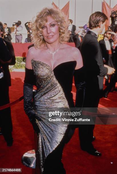 American actress Kim Novak, wearing a black-and-gold strapless evening gown with black evening gloves, attends the 61st Academy Awards at the Shrine...
