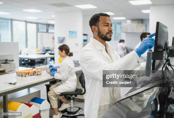 diverse male scientist analyzing data in laboratory - medical sample stock pictures, royalty-free photos & images