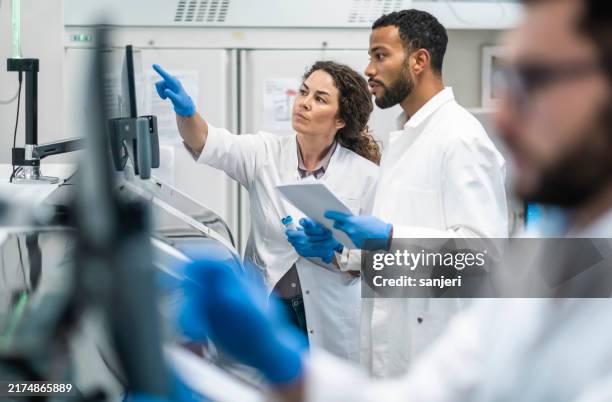 des collègues de laboratoire diversifiés dans une analyse réfléchie - équipement-de-laboratoire photos et images de collection