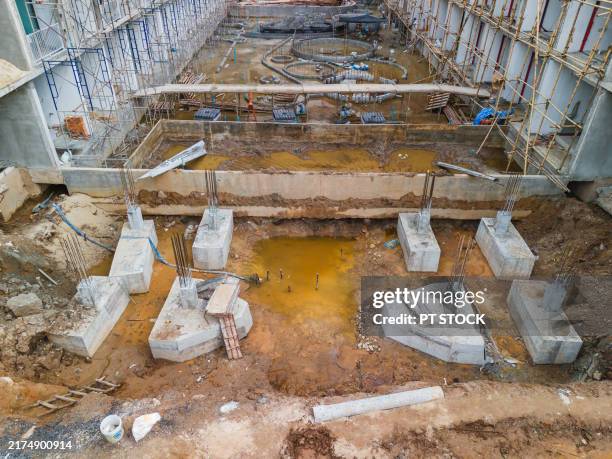 concrete foundation pillars with exposed rebar sit in a waterlogged construction site, surrounded by scaffolding, highlighting early-stage building development. - väg och vattenbyggnadsingenjör bildbanksfoton och bilder