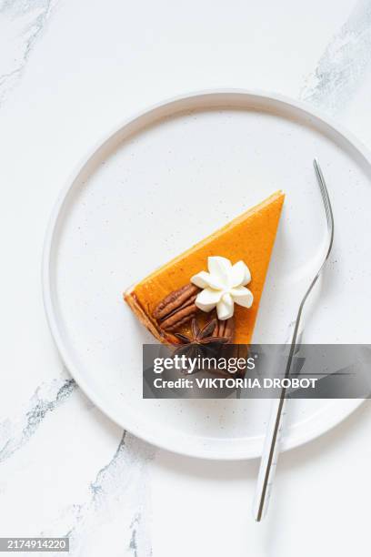 pumpkin pie with whipped cream in portions on a plate, on a light background. thanksgiving day, holiday concept. traditional american dessert, pastry. - taartpunt stockfoto's en -beelden