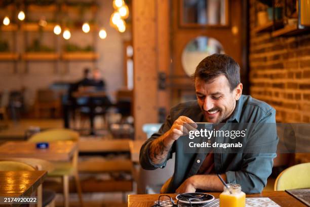 smiling man enjoying coffee in cafeteria - cafe culture stock pictures, royalty-free photos & images