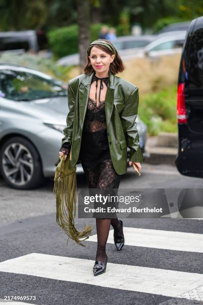 Guest wears dark green olive headband, shiny dark green olive oversized blazer jacket, black sheer mesh lace midi dress, dark green tassel bag, black...