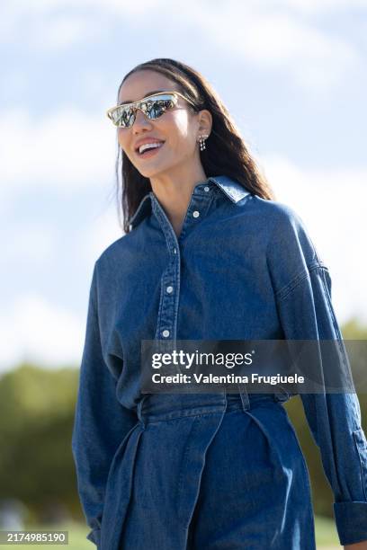 Tamara Kalinic wears gold sunglasses, silver earrings and a denim jumpsuit outside Loewe show during Womenswear Spring/Summer 2025 as part of Paris...