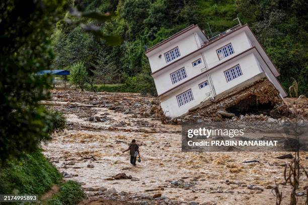 Man wades through the flood waters in the affected area of monsoon flooding in Roshi village of Nepal's Kavre district on September 30, 2024. Search...