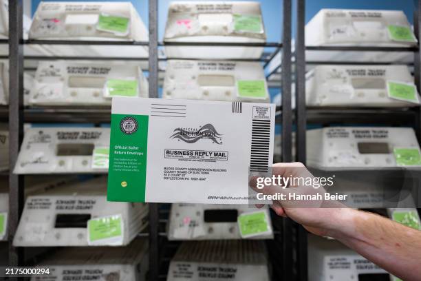 Director of the Board of Elections Tyler Burns holds a test ballot during a mail-in ballot processing demonstration at the Board of Elections office...