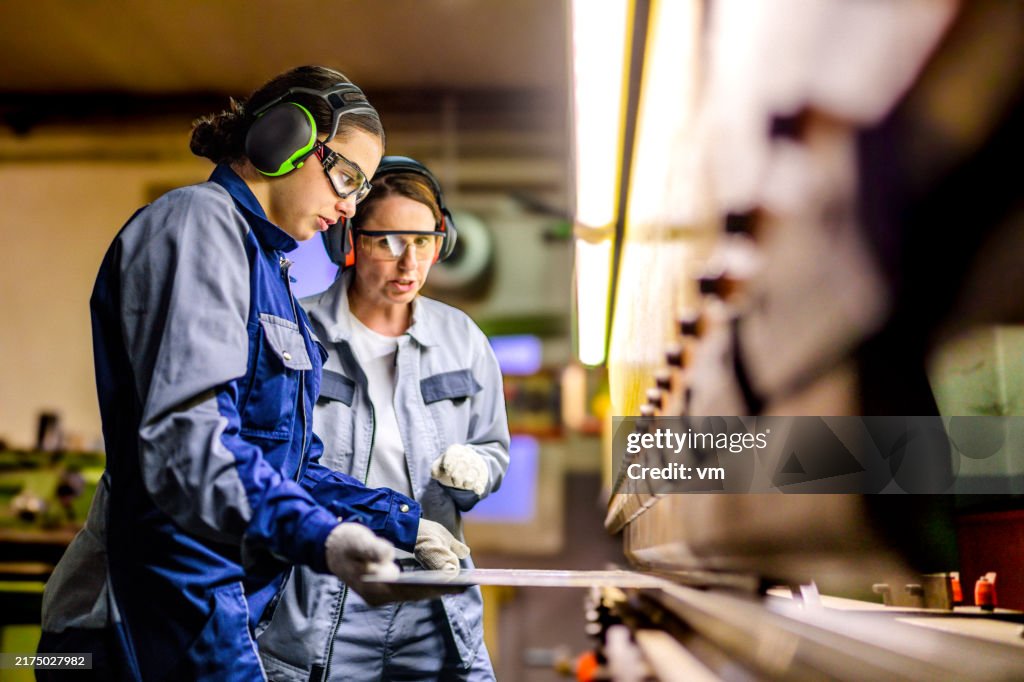 Skilled Female Workers Operating Press Brake in Industrial Setting