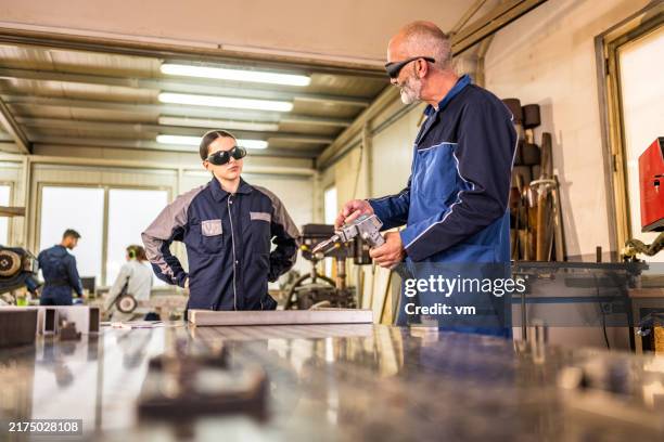 seasoned welder educates aspiring young woman in workshop - safety equipment stock pictures, royalty-free photos & images