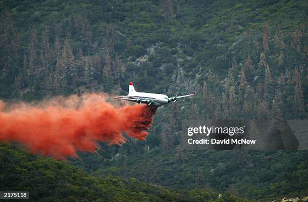 An airtanker drops fire retardant against a backdrop of dead trees, killed by bark beetles, as the Coyote Fire burns more than 13,000 acres of...