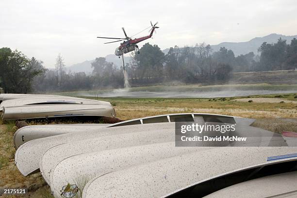 Firefighting helicopter picks up a load of water from a pond at the Lost Valley Boy Scout Camp where the scouts' conoes are stored as the Coyote Fire...