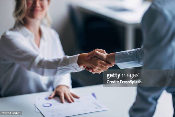 geschäftsleute, die sich am arbeitsplatz die hände schütteln - zuverlässigkeit stock-fotos und bilder
