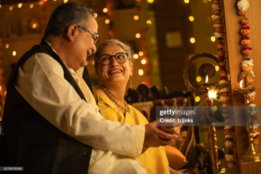 Cheerful senior couple burning sparklers at home during Diwali