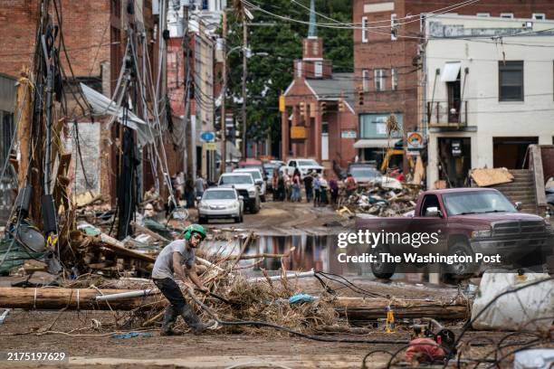 Marshall, NC Workers, community members, and business owners clean up debris in the aftermath of Hurricane Helene in Marshall, North Carolina on...