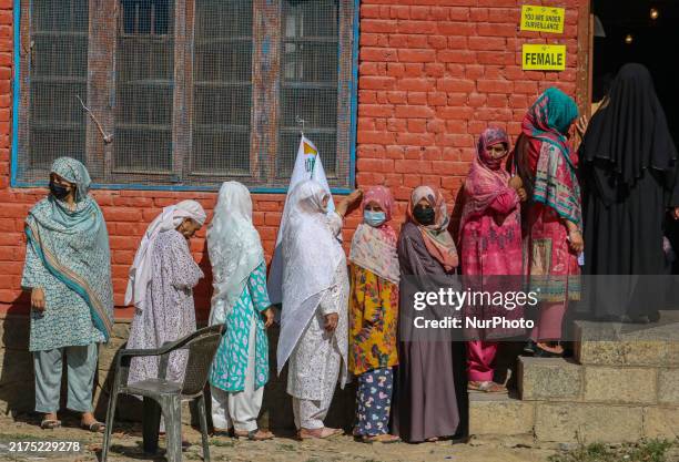 Women voters queue to cast their ballots at a polling station during the third and final phase of assembly elections in Shadipora, Sumbal area of...