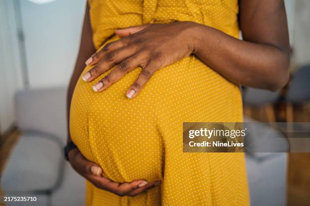 pregnant woman in dress holding her belly - black dress stock pictures, royalty-free photos & images