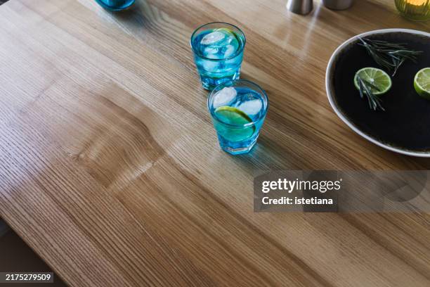 blue ice cold mocktail in glass with slice of lime - blue curacao stock pictures, royalty-free photos & images