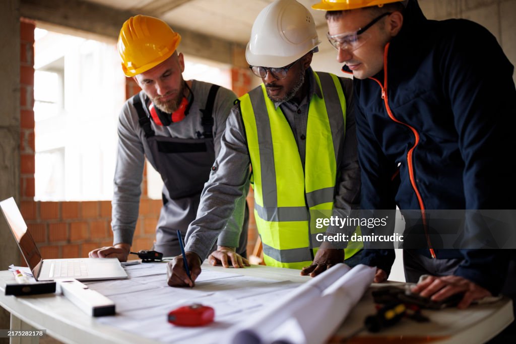 Engineer and construction workers discussing the blueprint project at the construction site