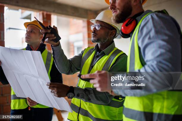 architect and engineers discussing blueprint at the construction site - construction mistake stock pictures, royalty-free photos & images