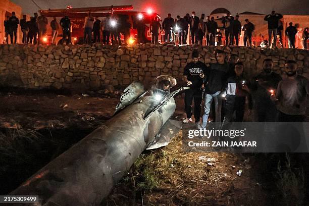 Palestinian youths inspect a fallen projectile after Iran launched a barrage of missiles at Israel in response to the killings of Lebanese Hezbollah...