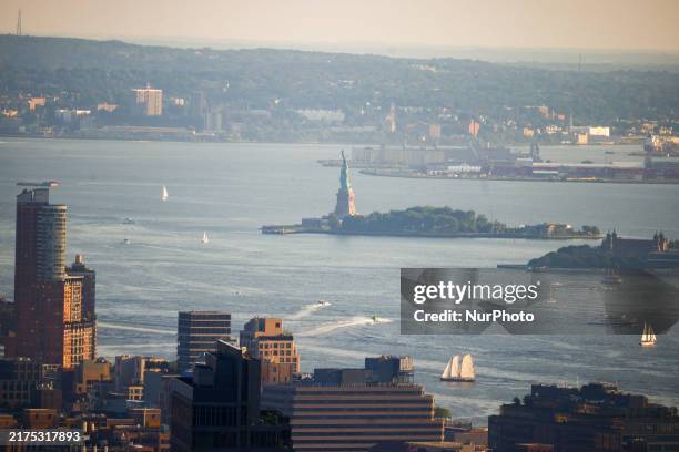 View on The Statue of Liberty at Liberty Island seen from Top of the Rock NYC Observation Deck of Rockefeller Center building in New York City,...
