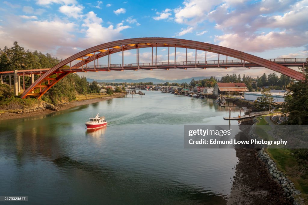 Historic Rainbow Bridge in the tourist town of La Conner, Washington with a boat passing underneath.
