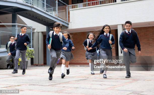happy school children running in the schoolyard - schooluniform stockfoto's en -beelden