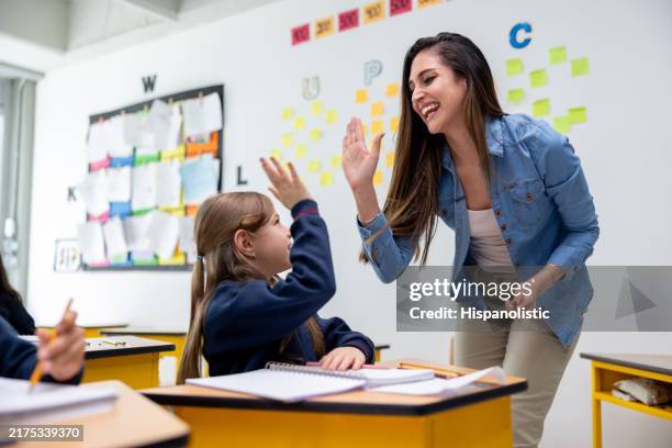 glücklicher lehrer, der einen jungen schüler in der klasse abklatscht - grundschulzeit stock-fotos und bilder
