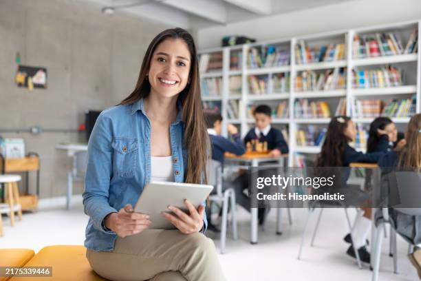 teacher smiling in the classroom and using a digital tablet - boy library stock pictures, royalty-free photos & images