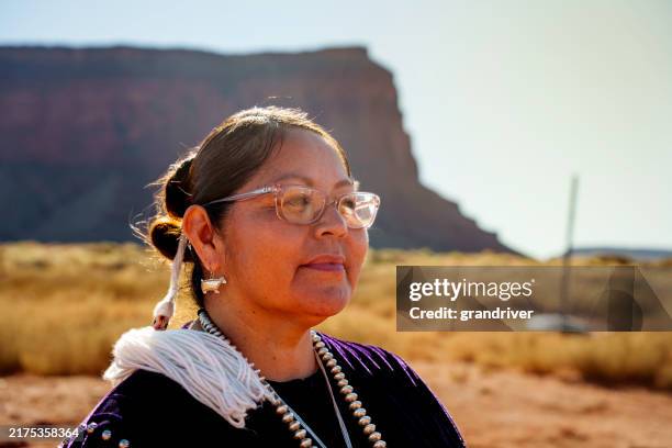 sunny portrait traditional navajo woman smiling at camera in the desert area of monument valley tribal park on the utah arizona border on a beautiful morning - native american reservation stock pictures, royalty-free photos & images