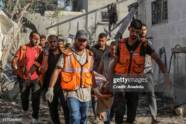 Civil defense teams and locals carry the lifeless body of a person during a search and rescue operation among the buildings which were destroyed by...