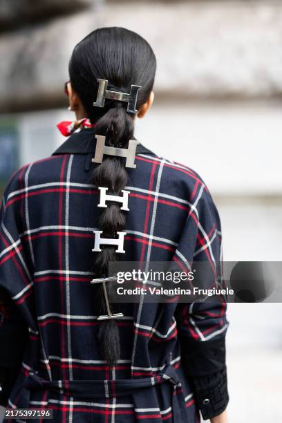 Guest wears Hermes silver hair accessories and a blue, red and white checked coat outside Hermes show during Womenswear Spring/Summer 2025 as part of...