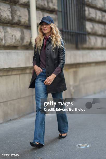 Guest wears navy blue baseball hat, dark brown long sleeve shirt, shiny black oversized blazer jacket, light blue denim jean pants, black pointed toe...
