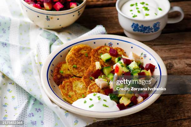 potato fritters with herring and vegetables on a plate - räucherfisch stock-fotos und bilder