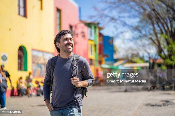 fröhlicher junger mann genießt die aussicht in caminito, la boca viertel, buenos aires, argentinien - caminito stock-fotos und bilder