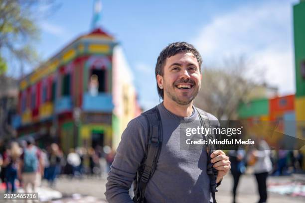 fröhlicher junger mann genießt die aussicht in caminito, la boca viertel, buenos aires, argentinien - caminito stock-fotos und bilder