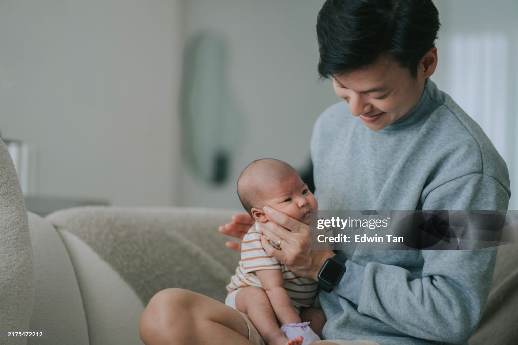 Asian chinese young father burping baby girl after milk in living room