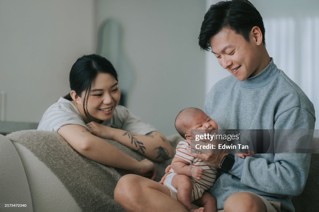 Asian Chinese parents burping baby girl in living room after feeding breastmilk
