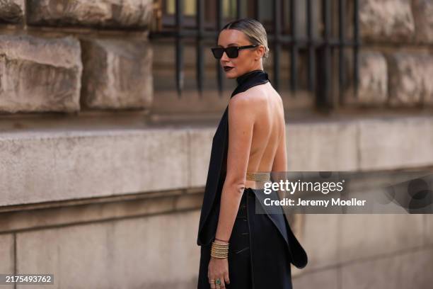 Nataly Osmann is seen wearing black squared sunglasses; a dark denim halter neck top with an open back and a train draping down one side featuring...