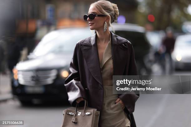 Leonie Hanne is seen wearing burgundy oval sunglasses with logo-embellished temples from Celine; shiny silver earrings in a large organic shape from...