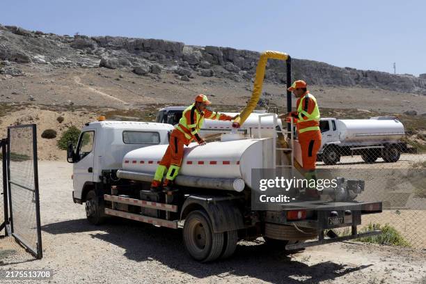 Workers fill a tank with water treated in a mobile desalination station also called "monobloc", in Beddouza in western Morocco on July 23, 2024. As...