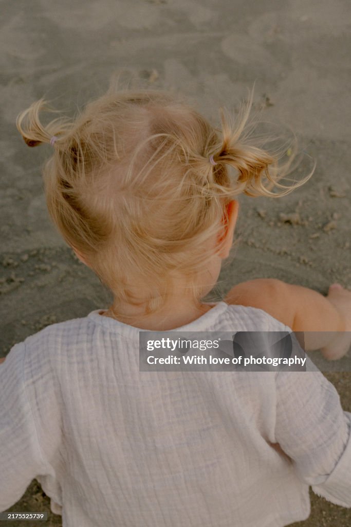 Cute little toddler girl 1-2 year old in white cloths on the beach coastline lifestyle enjoying vacation