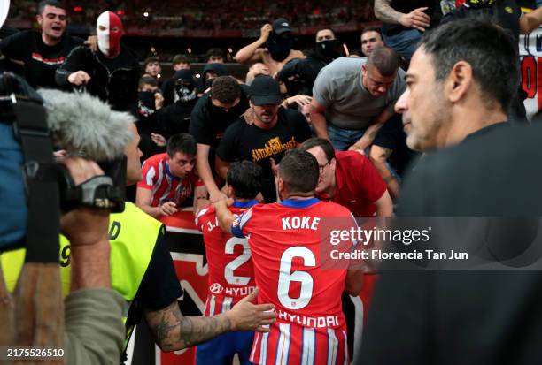 Jose Gimenez and Koke of Atletico de Madrid interacts with fans after objects are thrown at Thibaut Courtois of Real Madrid causing the game to be...
