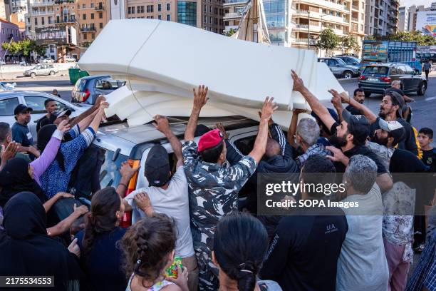 Group of refugees throw themselves on a car to try to grab a mattress outside the mosque in Beirut's Martyrs' Square. With more than 1 million...