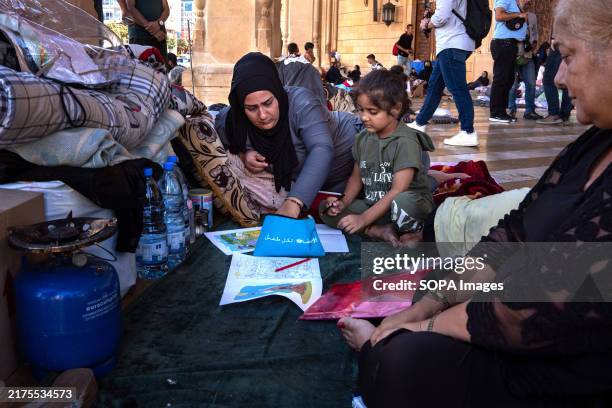 Refugee woman displaced from Bahiye, seen with her daughter on a carpet laid out at the Grand Mosque in Martyrs' Square where they are taking...